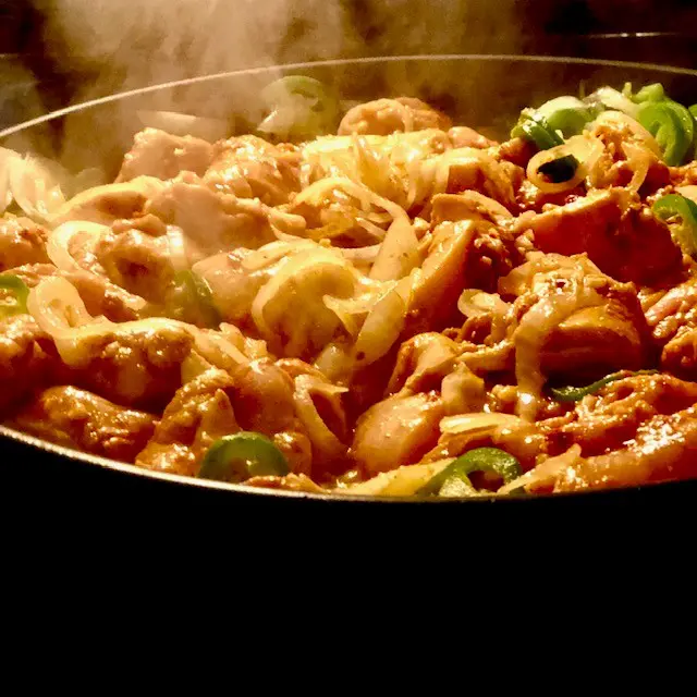 chicken thighs cooking with onions and peppers
