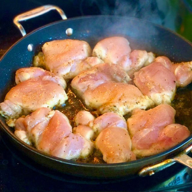 Boneless chicken thighs cooking in a pan